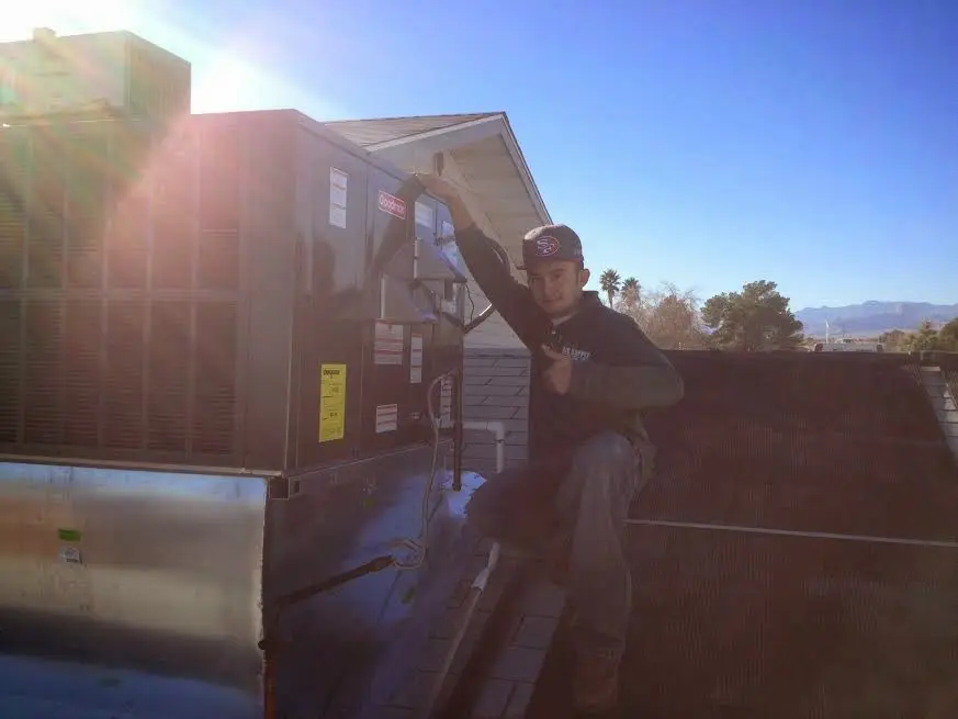 HVAC technician performing AC Tune-Up on a rooftop unit in Orange Cove